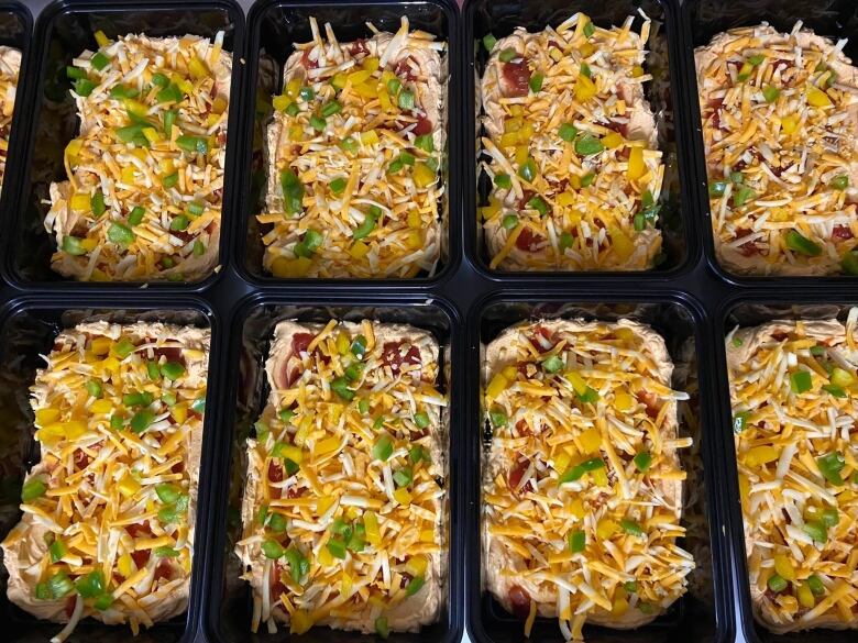 Containers full of taco dip  made with cheese, cream cheese, peppers and spices.