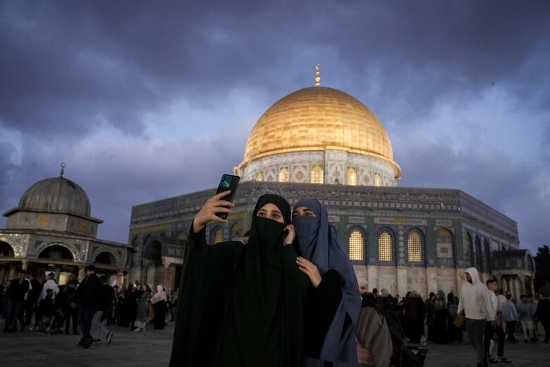 Two women in niqabs take a selfie in front of the Dome of the Rock during first day of Eid.