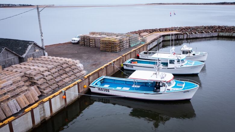 Three fishing boats tied up to a wharf 