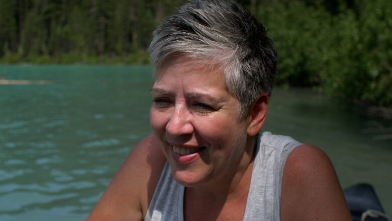 A woman is pictured smiling by a body of water. 