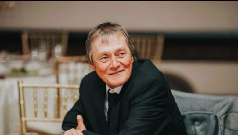 A man sits in a suit at a table.