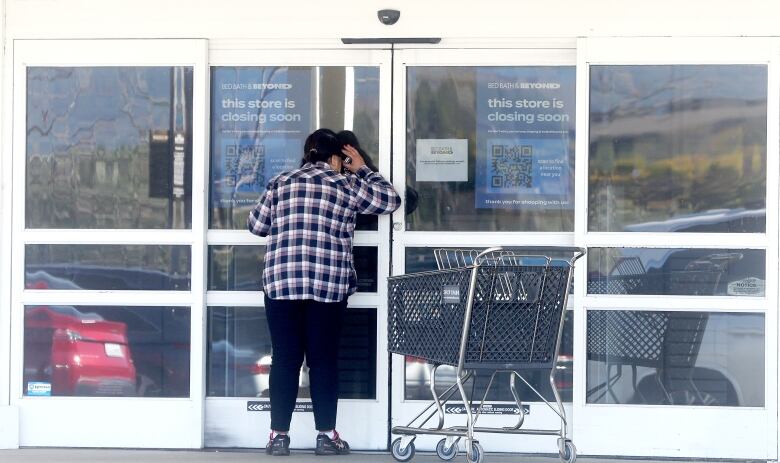 A person looks through the glass doors of a Bed Bath and Beyond store.