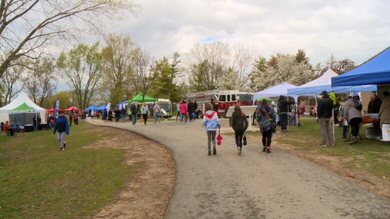 People walking along a path passing by outdoor tents