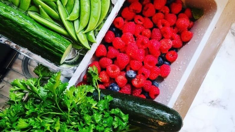 Plates and bowls with fresh vegetables and berries.