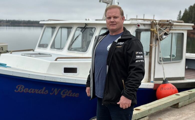 A man stands next to his fishing boat 