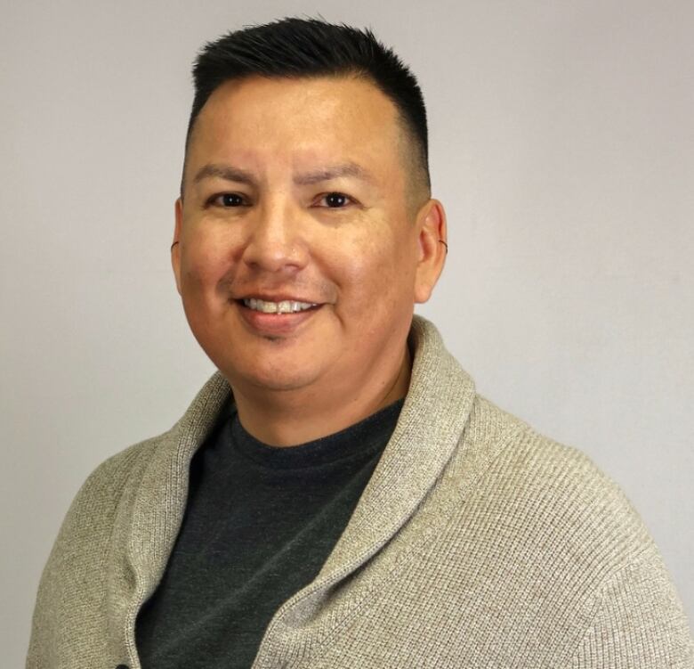 Man posing for a photo wearing a sweater in front of a white background