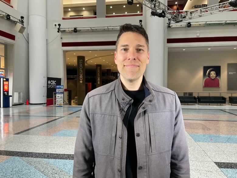 A man is shown smiling in the CBC building's atrium in Toronto