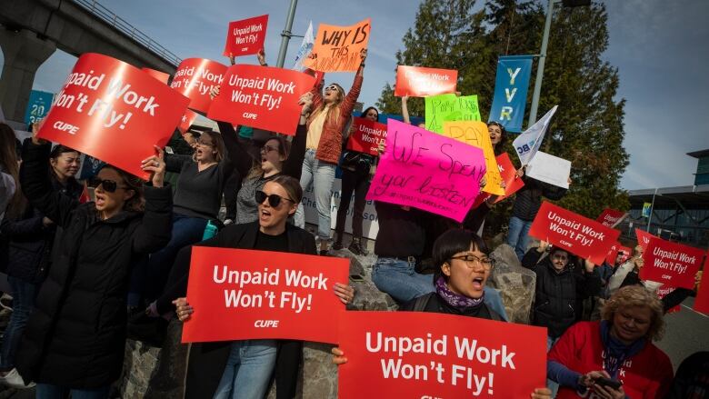 A number of people hold up placards reading 'Unpaid work won't fly' and other signs at a protest.