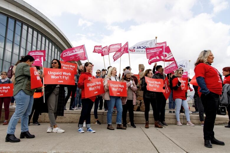 A number of people at a protest hold up signs reading 'Unpaid work won't fly!'.