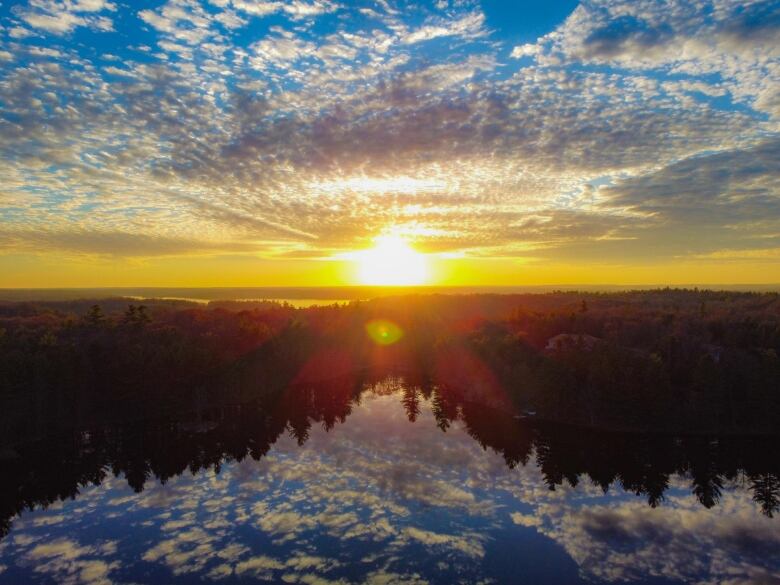 Sunset occurring over a lake surrounded by forest. 