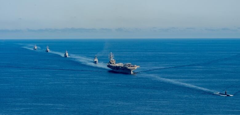 An aerial shot shows warship in a body of water.