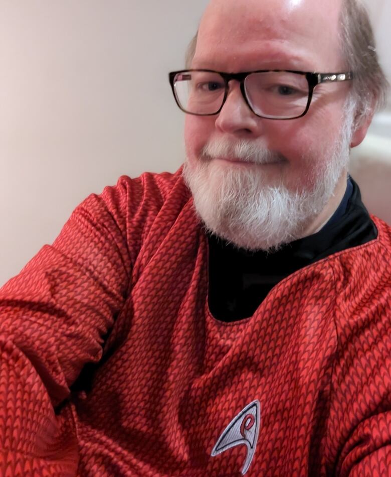 A man smiles wearing a Star Trek shirt.