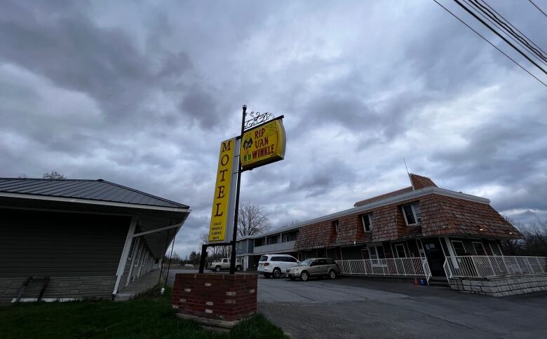 A small motel with a yellow sign is shown on a cloudy day.