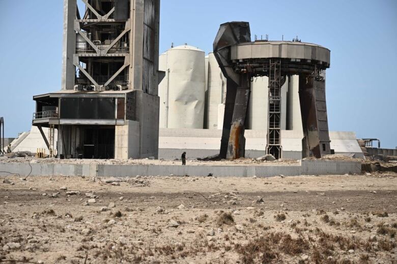 A small figure stands among the damage of a SpaceX launch pad in Boca Chica, Texas.