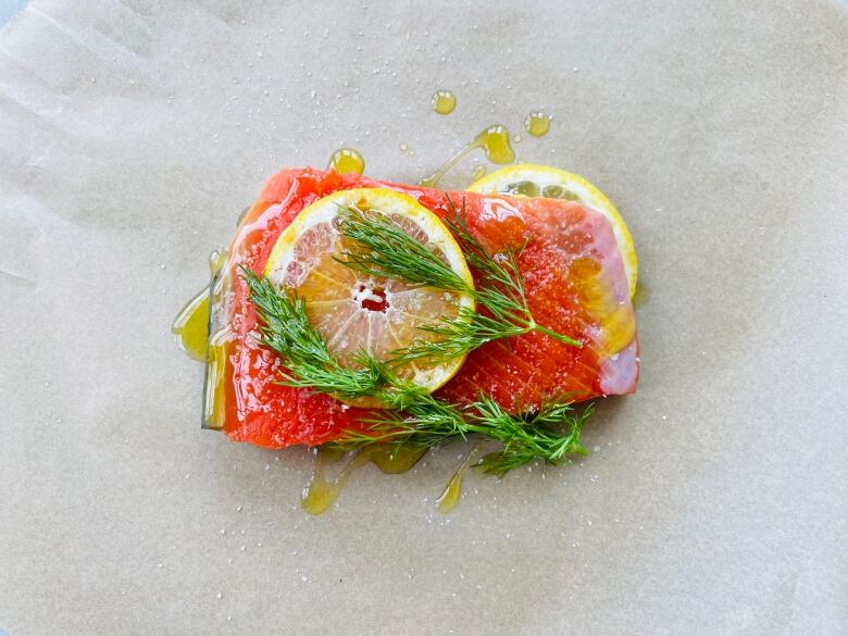 A salmon fillet covered in oil, lemon and dill.