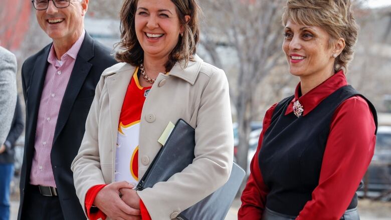 Business and political leaders smile during an outdoors announcement.