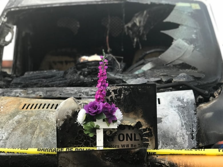 Purple flowers on a burned van with yellow police tape around them