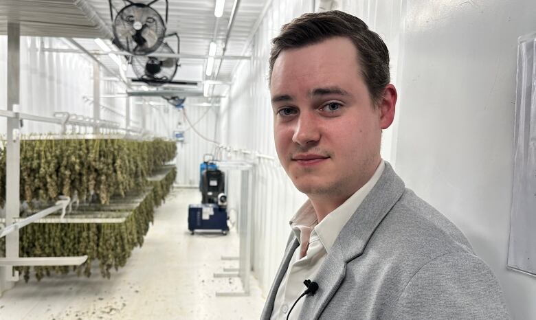 A man wearing a grey suit stands in the doorway of a cannabis drying room.