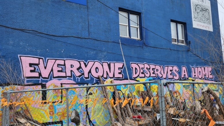 On a blue building, graffiti written in pink spells 