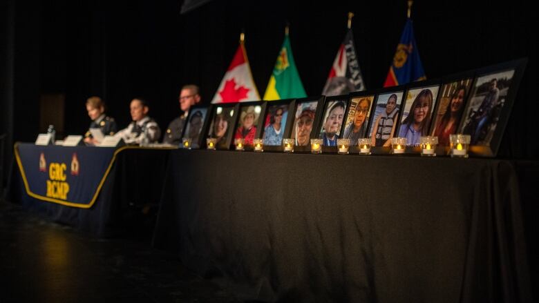 Photos of the victims of the mass casualty homicides in James Smith Cree Nation and nearby Weldon, Sask. are sitting on a table in Melfort. RCMP can be seen in the background presenting a timeline to media. 