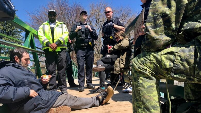 people sitting on ground. police in back