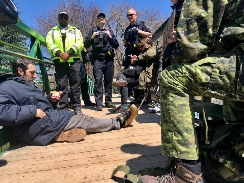 people sitting on ground. police in back