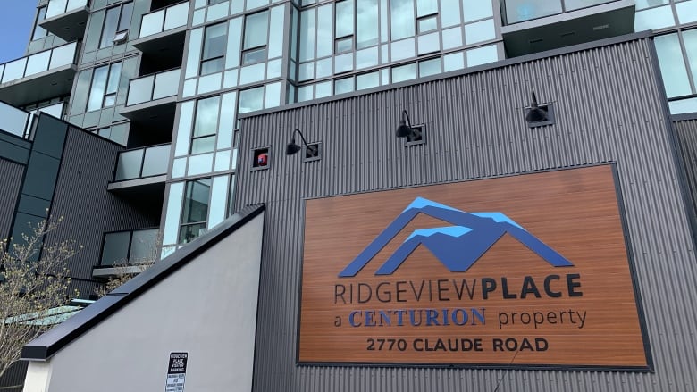 A sign outside a glass apartment highrise reads 