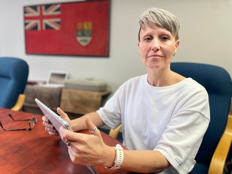 Kelly Hamilton holds a tablet with job listings on it, as she sits at a desk in the Island Recruiting office. 