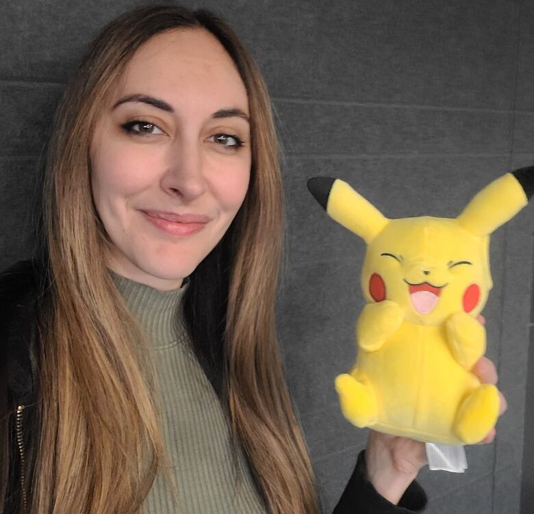 A woman poses with a Pikachu doll.