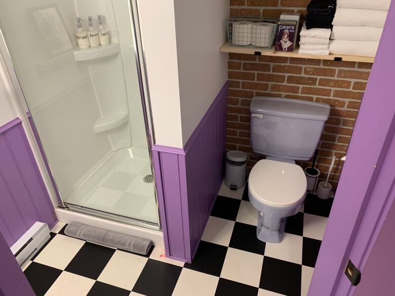 A bathroom with purple walls and black and white tile floors to look like Monica's apartment in Friends