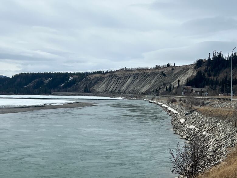 A view of a river and road running alongside it, at the base of an escarpment.