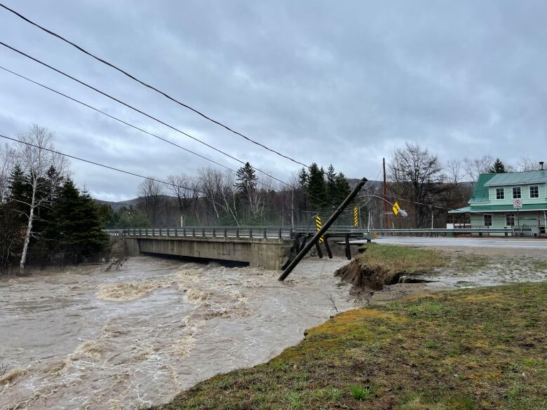 Part of a bridge collapsed near rushing water. 