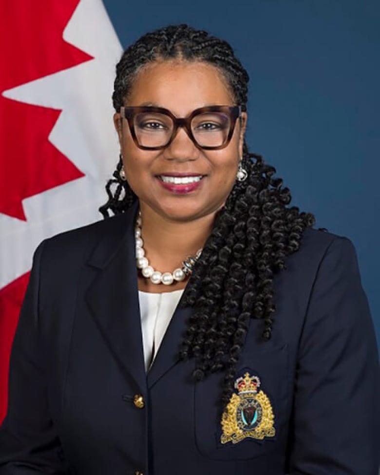 A woman is pictured in an RCMP blazer in front of a Canada flag. 