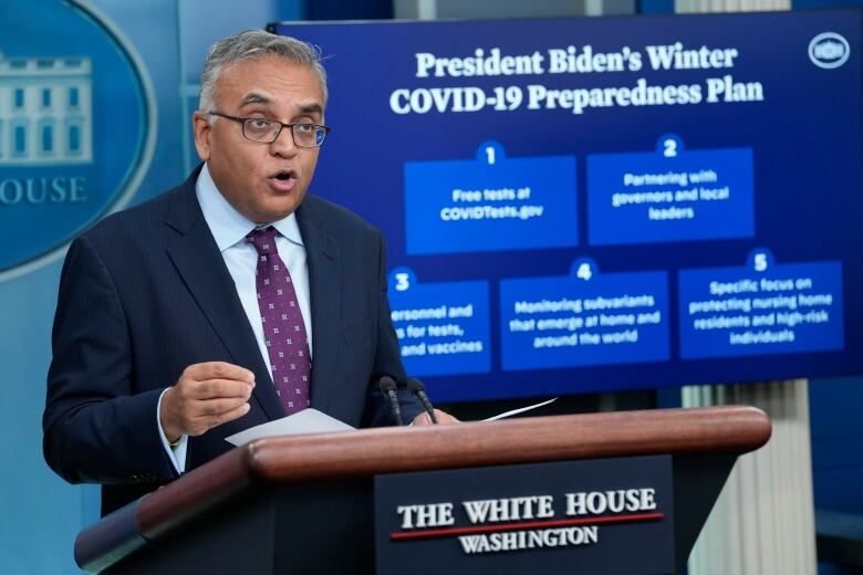 A person gestures while speaking at a lectern.