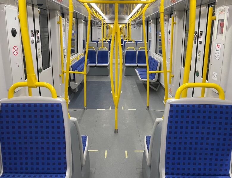 The inside of an empty light rail train with blue seats at night.