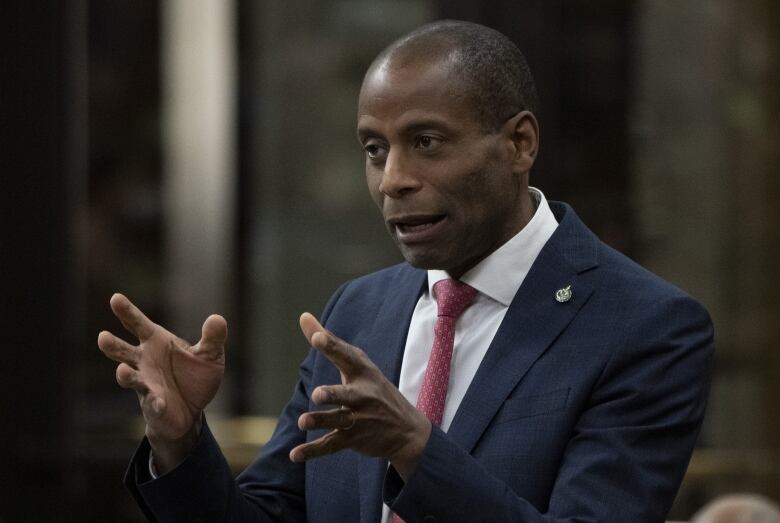 A politician gestures with both hands as he speaks in a legislature.