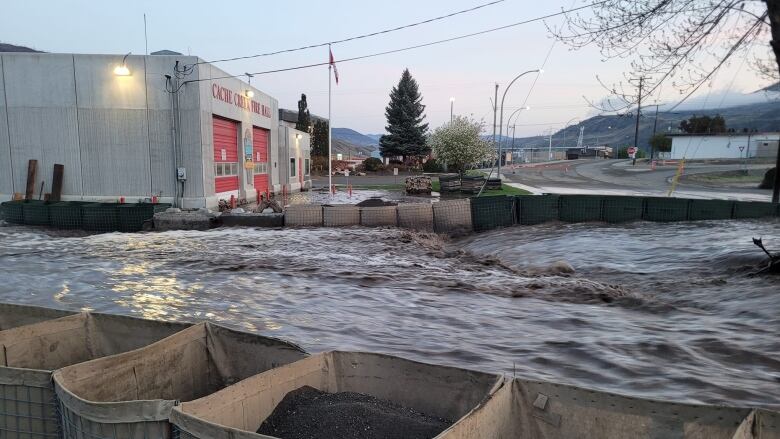 Sand bags and barriers surround the Cache Creek fire hall as flood water rises