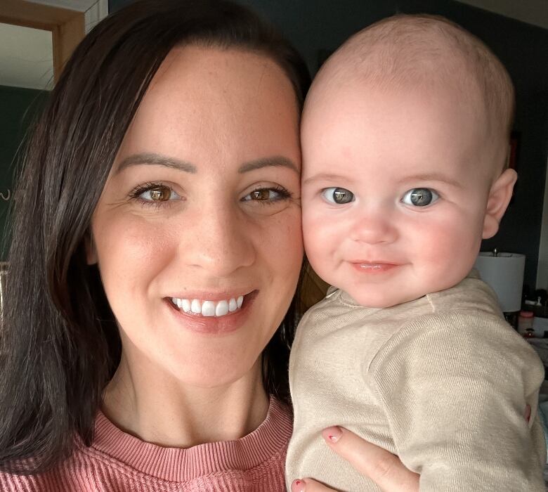 A woman in a pink shirt is holding a smiling baby.