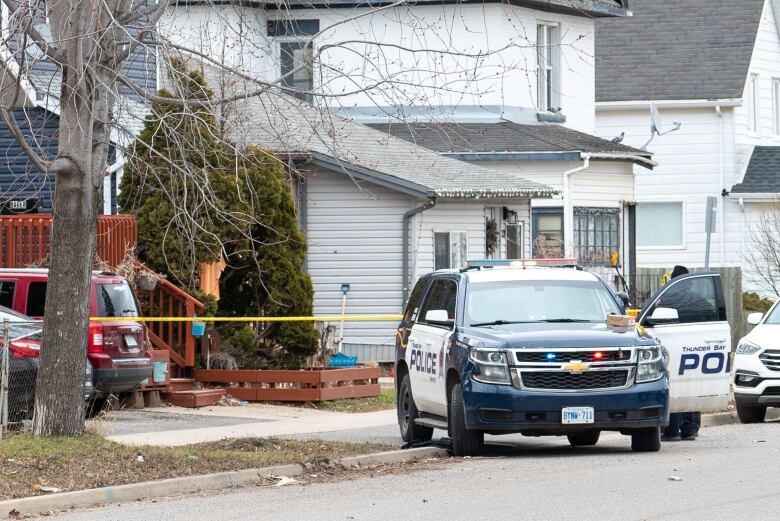 A police vehicle is parked on a street. It's in front of yellow police tape. 