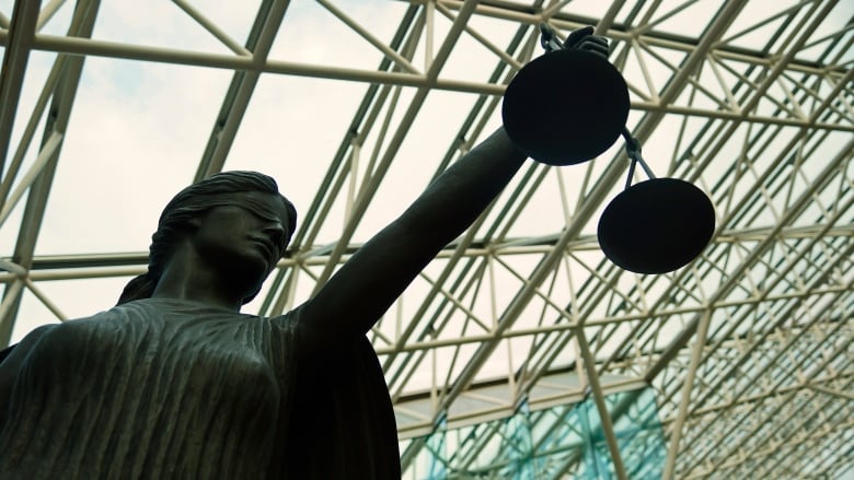 A statue of a blind goddess holding the scales of justice in a court atrium.