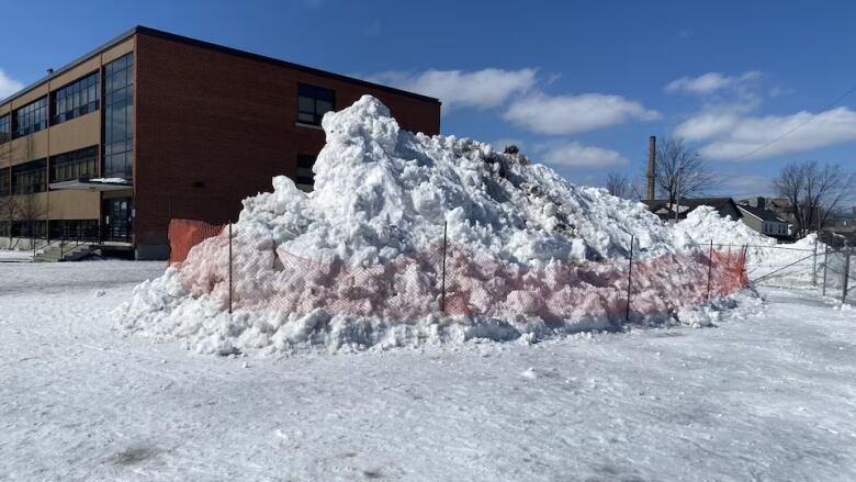 A pile of snow is sectioned off in a schoolyard. 