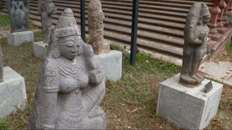 Stone statues line a lawn.