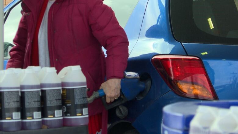 A woman pumps gas into a car.