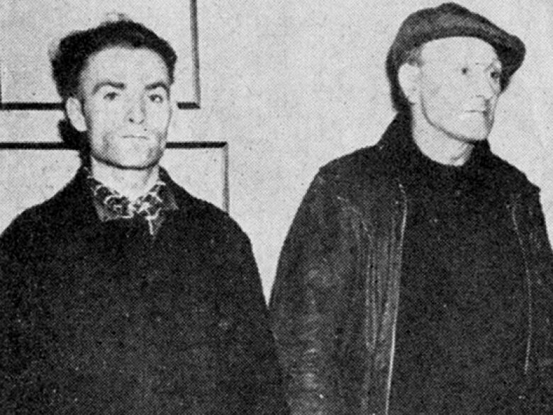 An old black and white photo of two men in dark clothes.