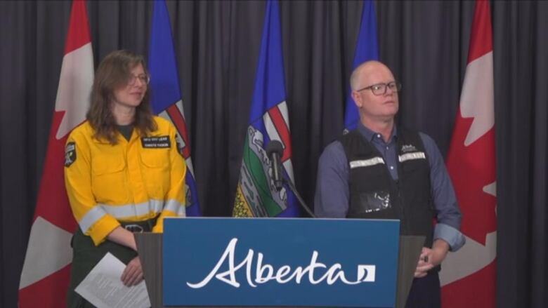 A woman and a man stand at a podium. 