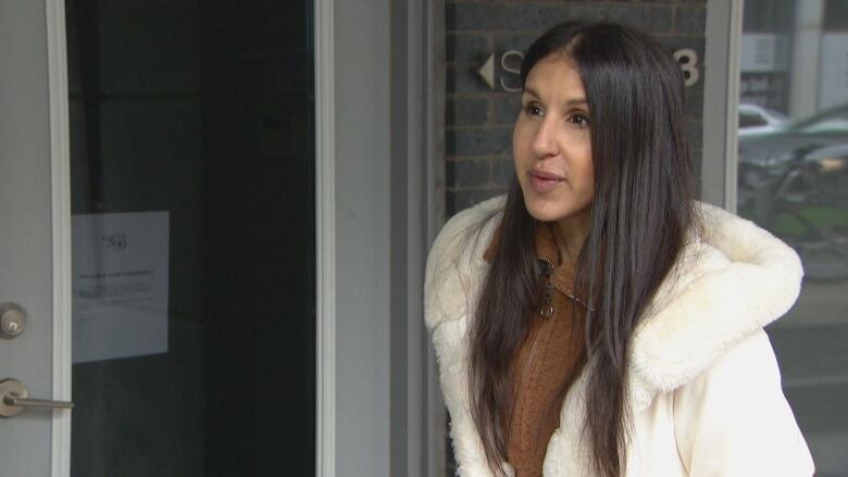 A woman does an interview in front of a condo building.