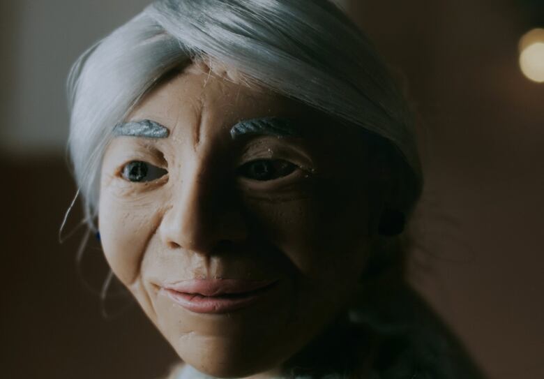 A clay model of an elderly women with white hair. 