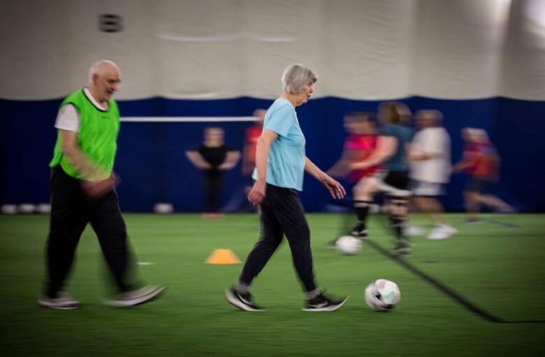 A senior walks with a soccer ball at her feet.