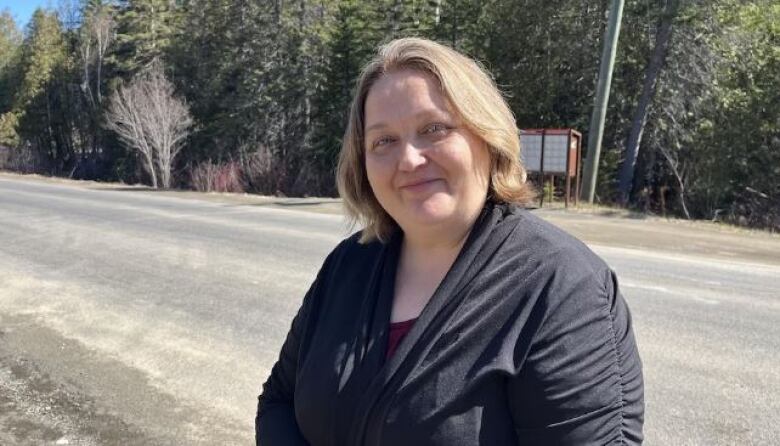 Woman stands in front of a community mailbox. 