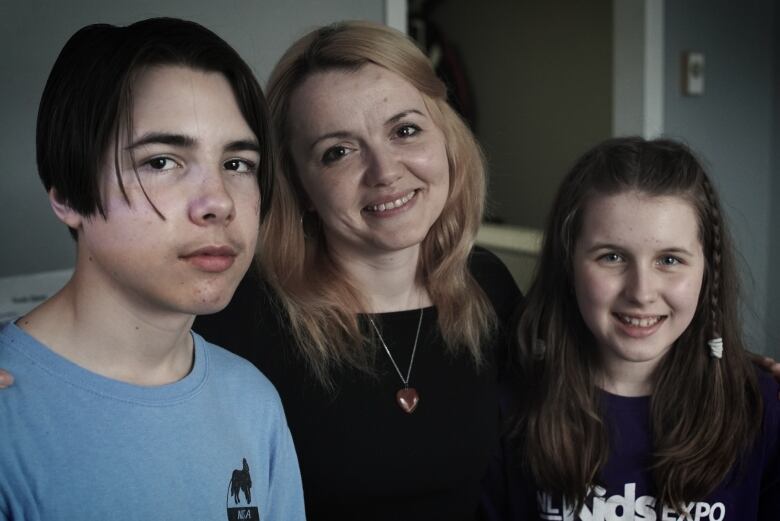 A mother and her two children smile and pose for a picture.